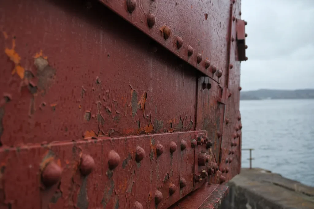 Närbild av svetsad stålbalk i vittrad roströd färg med bultrader