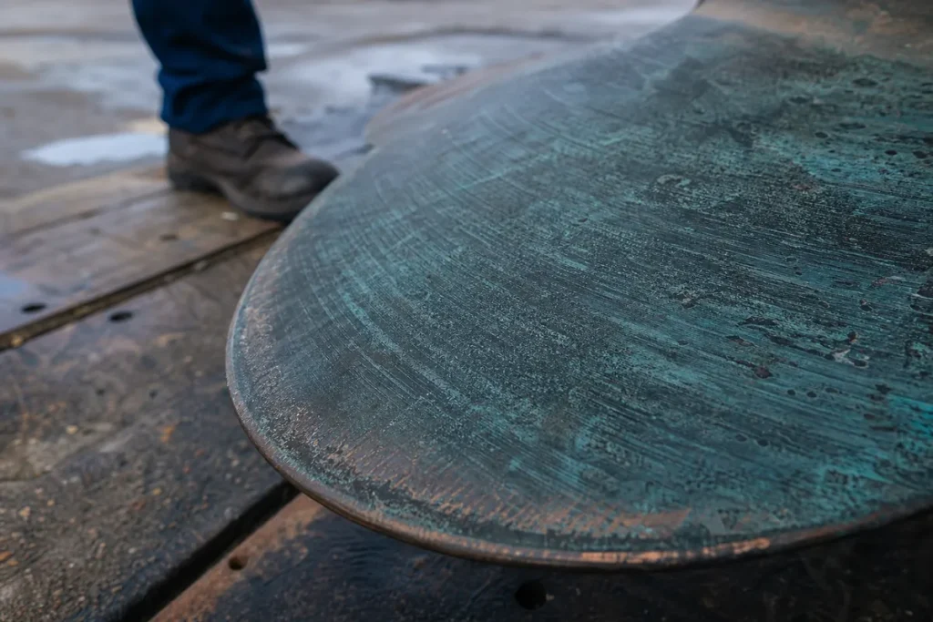 Närbild av kanten på ett stort bronspropellerblad med grön patina